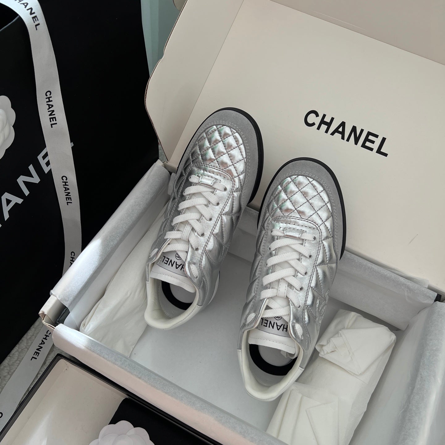 Chanel quilted metallic sneakers with white laces and black trim, front pair