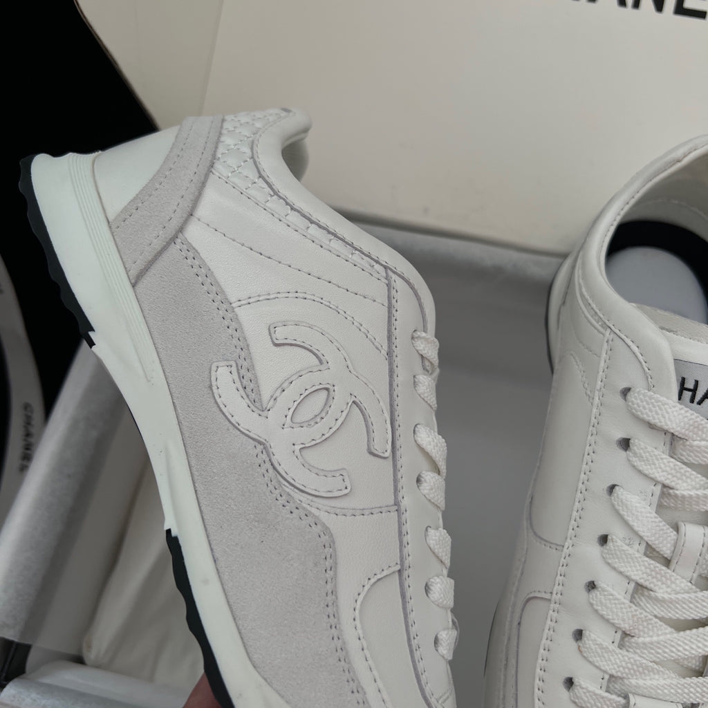 White Chanel unisex sneaker with embossed side logo and lace-up detail.