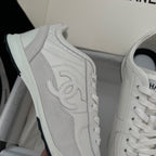 White Chanel unisex sneaker with embossed side logo and lace-up detail.