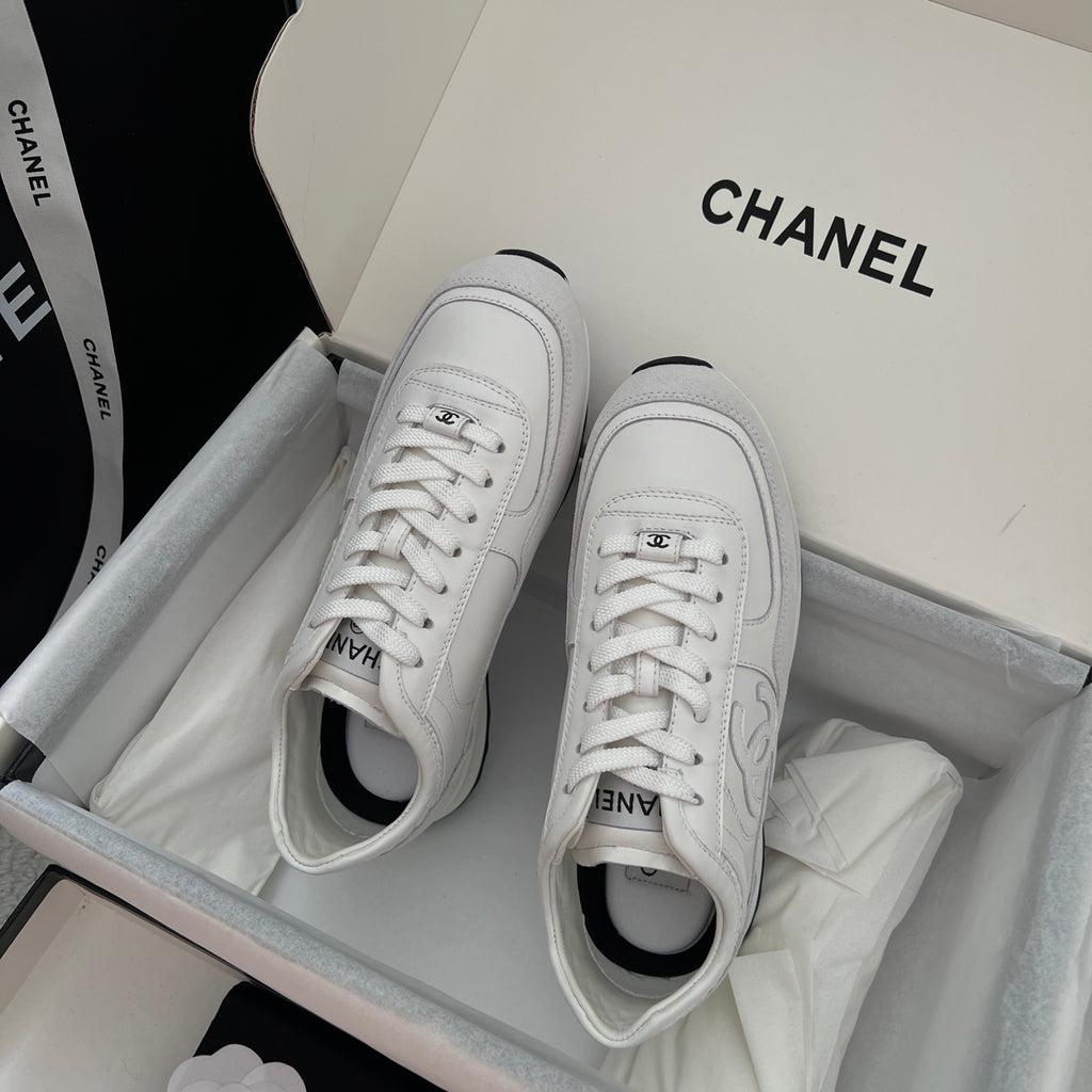 White Chanel unisex sneakers with lace-up front and rounded toe opening.