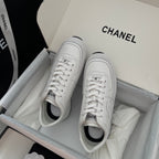 White Chanel unisex sneakers with lace-up front and rounded toe opening.