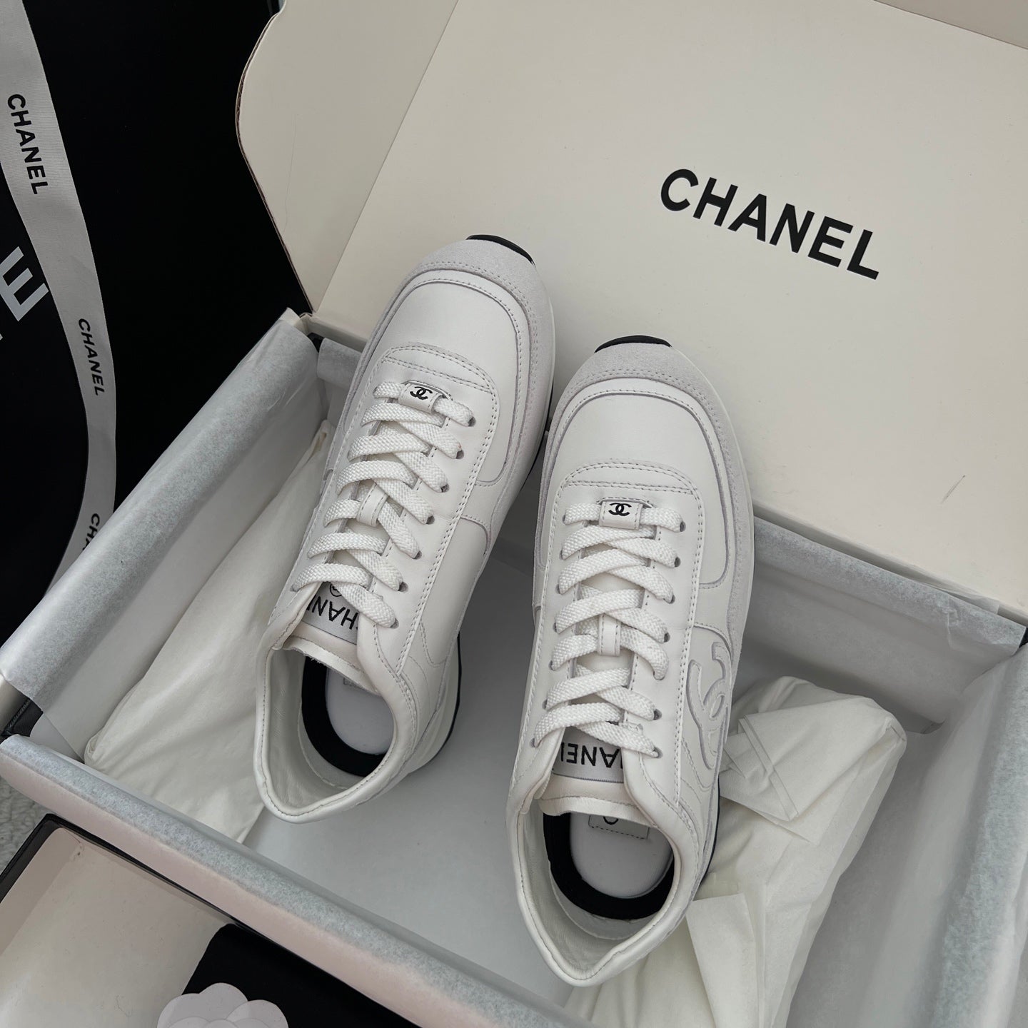 White Chanel unisex sneakers with lace-up front and rounded toe opening.