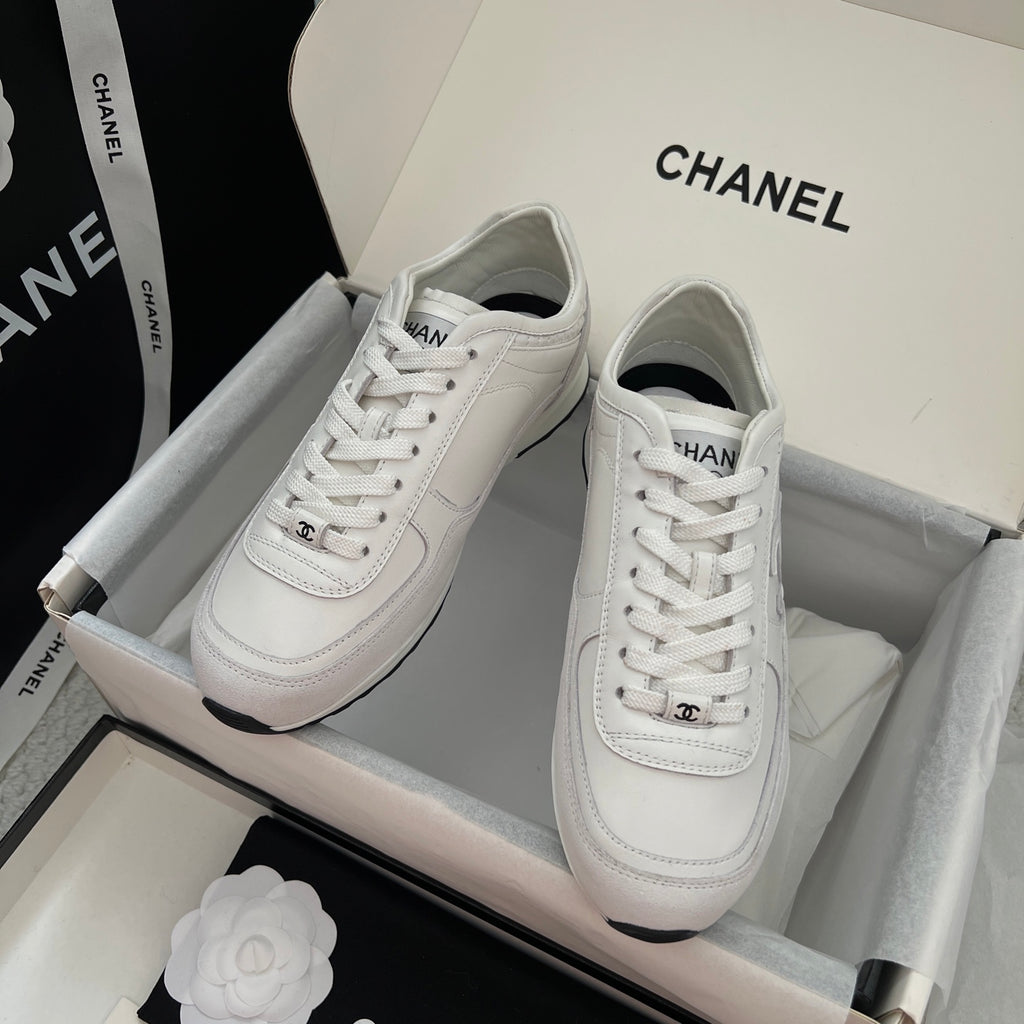 White Chanel unisex low-top sneakers with lace-up closure and logo patch.