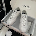 White Chanel unisex low-top sneakers with lace-up closure and logo patch.