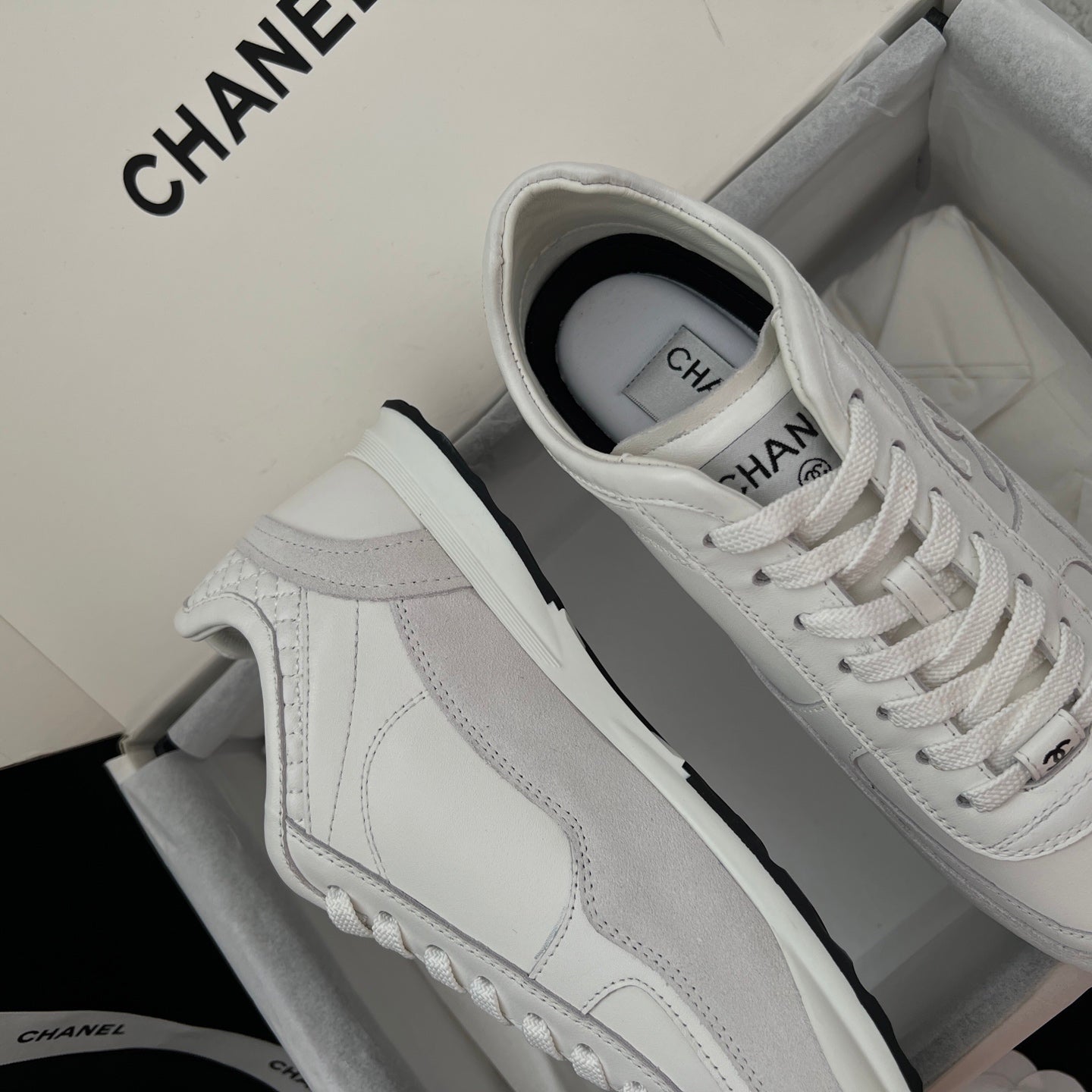 White Chanel unisex low-top sneakers with side panel stitching and lace-up.
