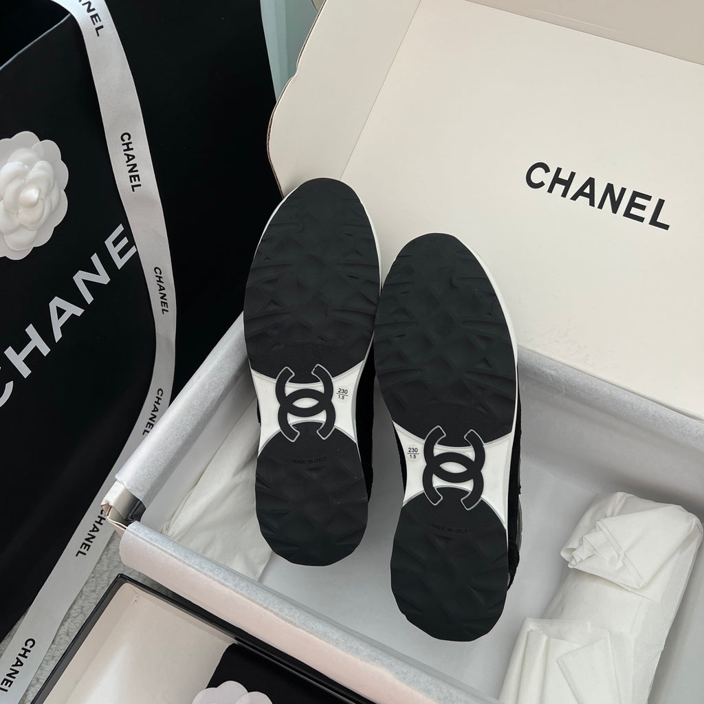 Black Chanel unisex sneakers showing outsoles with white logo details