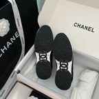 Black Chanel unisex sneakers showing outsoles with white logo details
