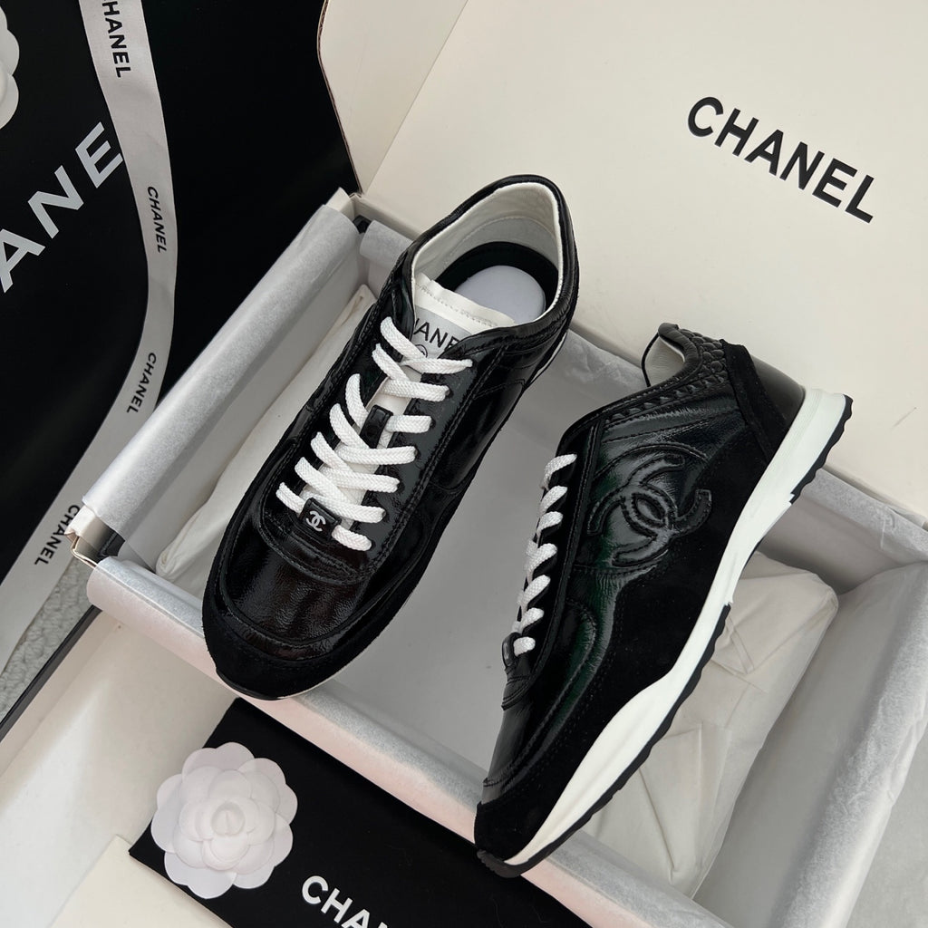 Pair of black Chanel unisex sneakers with white midsoles, side view