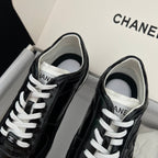 Black Chanel unisex sneakers, front view with white laces and logo tongue