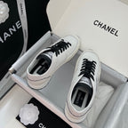 Pair of white leather sneakers with black laces and Chanel logo on insoles