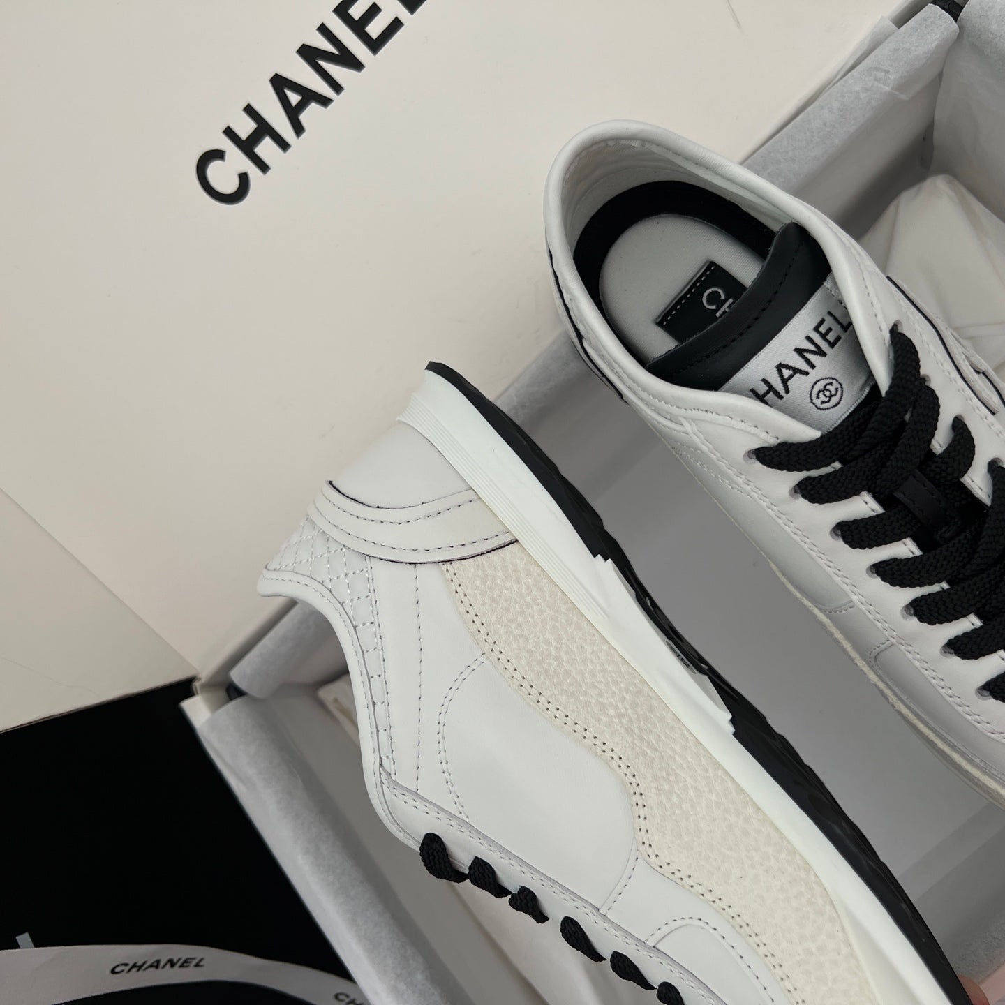 White leather sneakers with black laces and side Chanel emblem, low sole