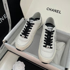 White leather sneakers with black laces and Chanel logo on tongue