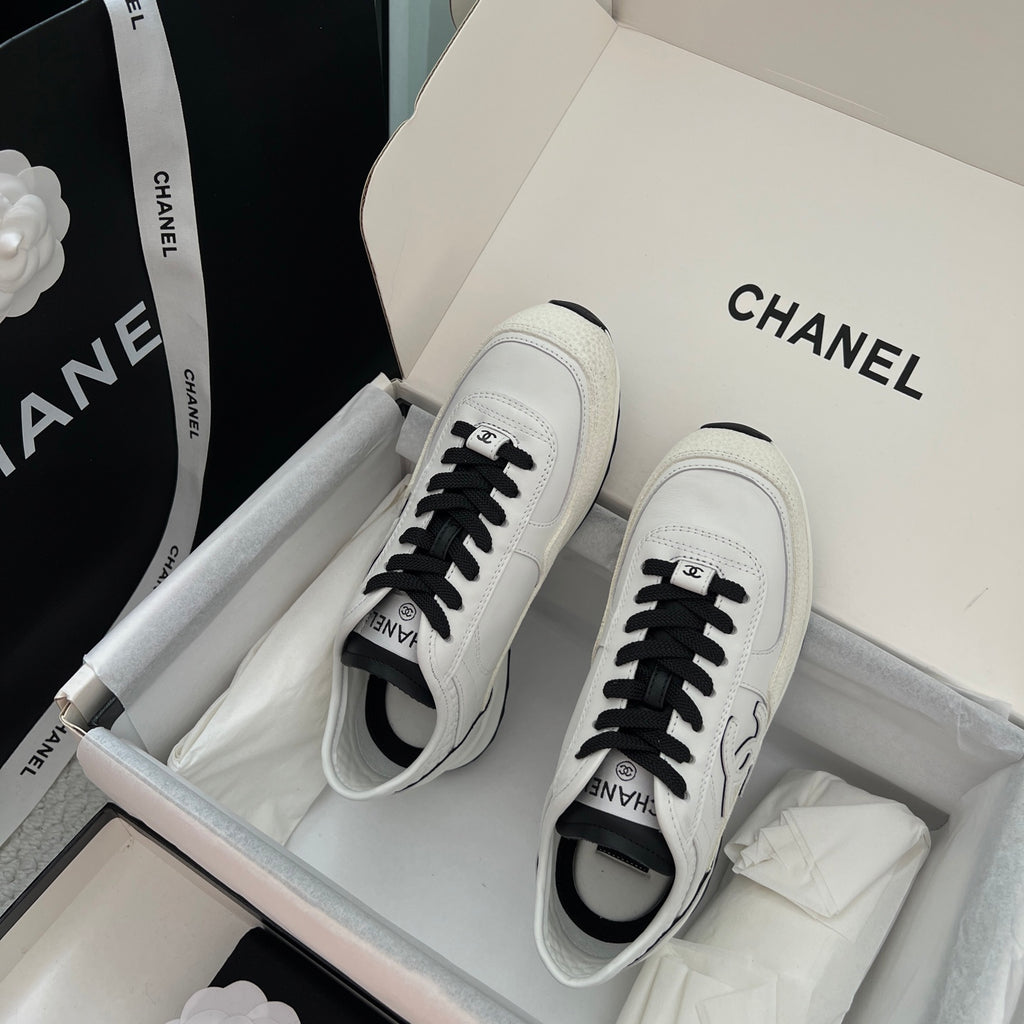 White leather sneakers with black laces and side Chanel logo, front view
