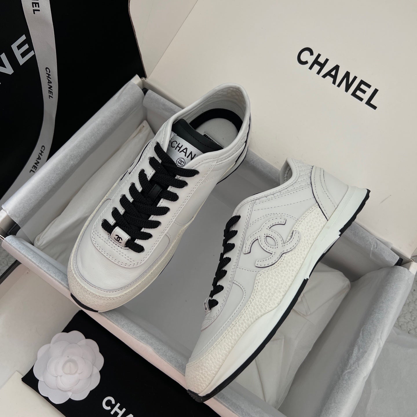 White leather sneakers with black laces and side Chanel logo