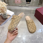 Gucci beige GG monogram slide sandals with light pink footbeds, one held by hand
