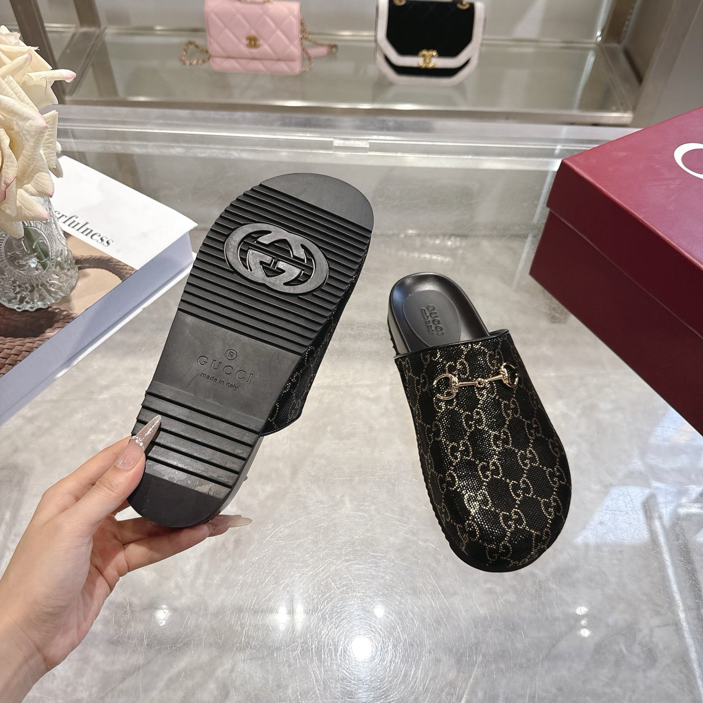 Gucci slide sandals with dark GG monogram upper; view of black textured outsole tread.