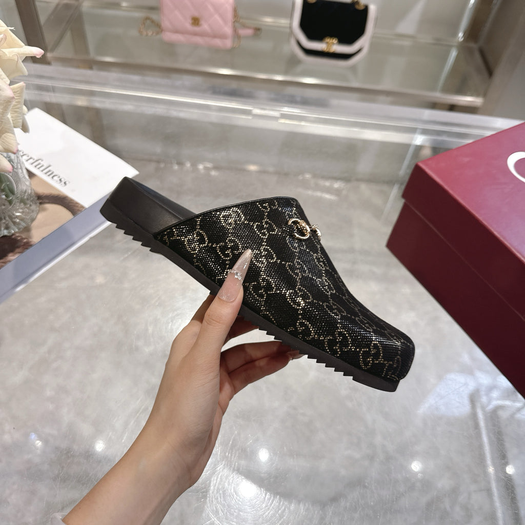 Gucci ankle-height slide bootie style in dark GG monogram fabric with gold horsebit detail.
