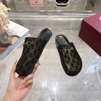 Gucci slide sandals with dark GG monogram pattern and gold horsebit detail on black straps.