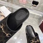 Gucci slide sandals close-up of black footbed and dark GG monogram upper with gold horsebit.