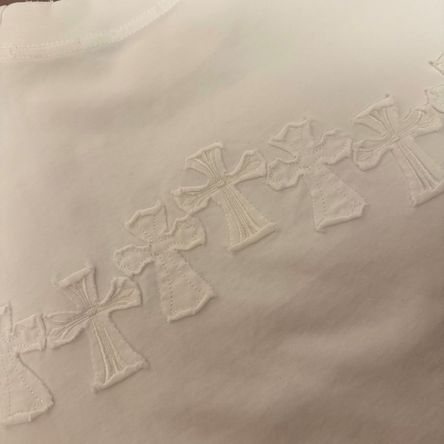 White T-shirt with row of raised embroidered cross motifs