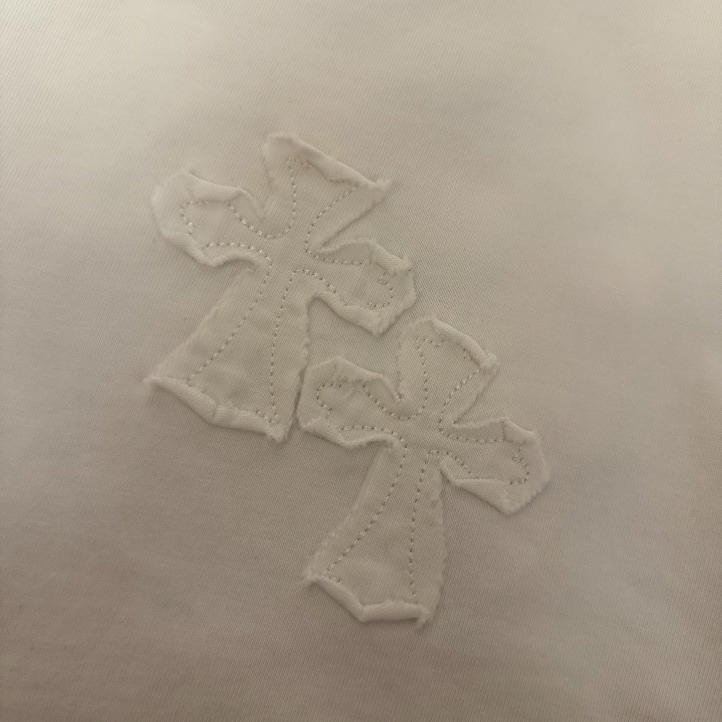 White T-shirt chest graphic with raised embroidered cross pattern