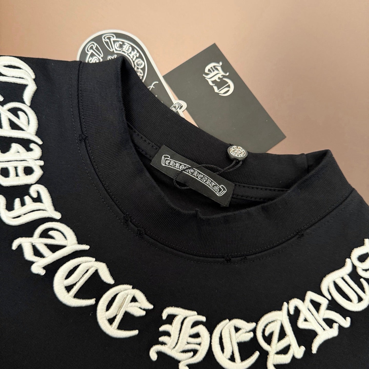 Black crew-neck T-shirt collar with white logo embroidery and neck tag