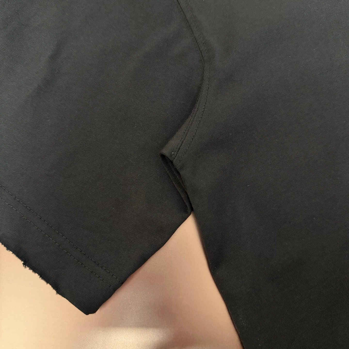 Black short-sleeve T-shirt sleeve and side seam with stitched hem detail
