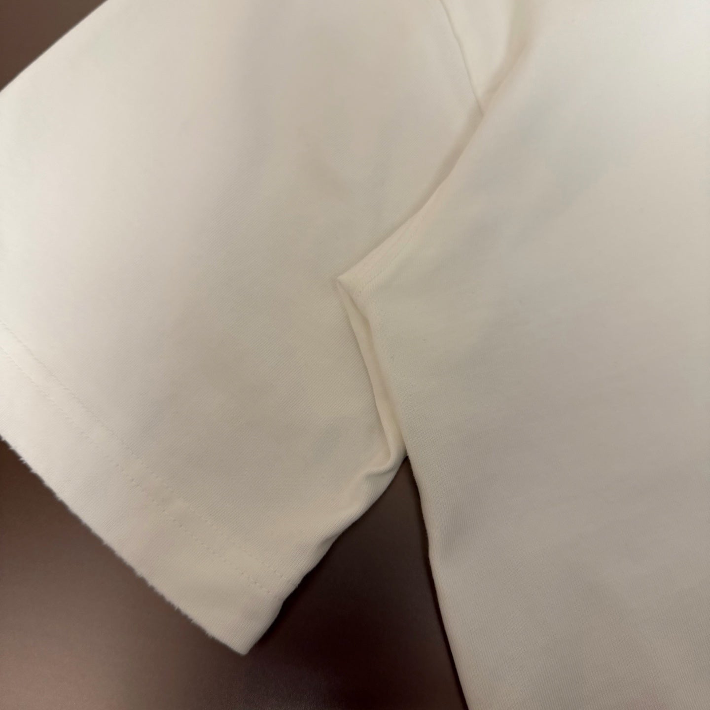 White short-sleeve T-shirt side panel close-up, fabric texture visible