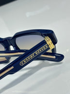 Chrome glasses close-up: navy frame with gold logo detail