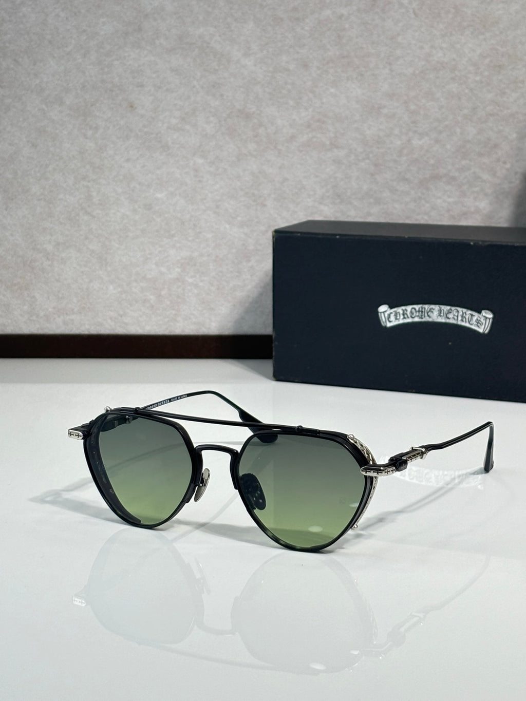 Chrome glasses with green-tinted lenses and black metal frame, round oversized shape