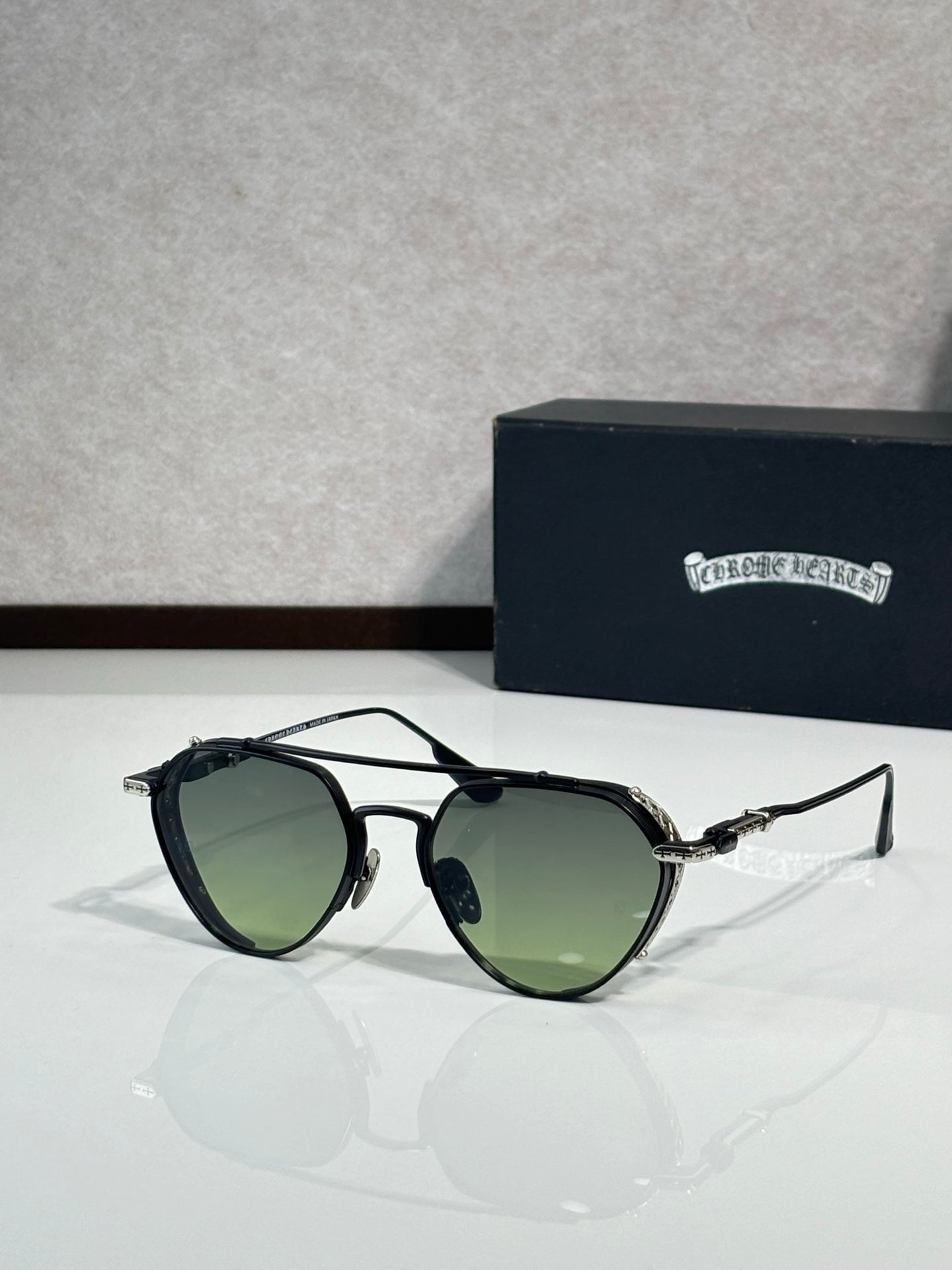 Chrome glasses with green-tinted lenses and black metal frame, round oversized shape
