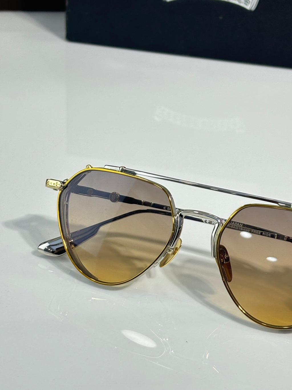 Chrome glasses close-up with gold-tone frame and amber-tinted lenses