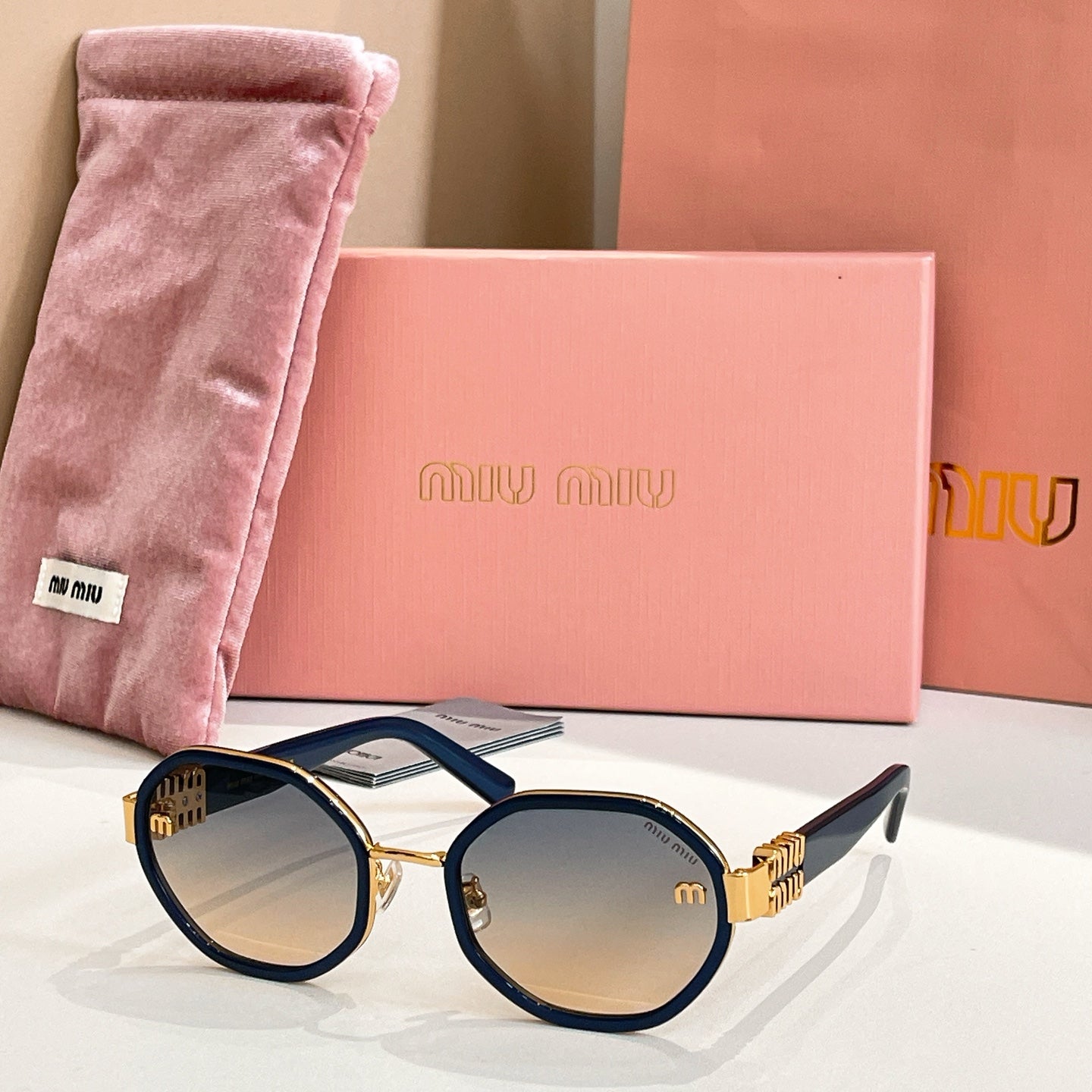 MiuMiu round sunglasses with navy frames and gold-tone logo arms