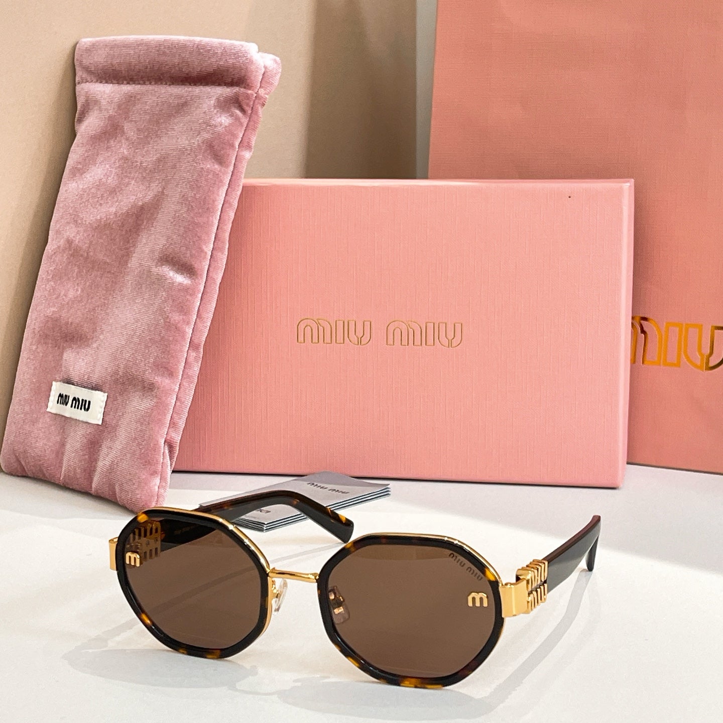 MiuMiu round sunglasses with dark tortoiseshell frames and gold-tone logo arms