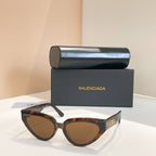 Balenciaga sunglasses with dark frames and brown-tinted lenses, gold logo temple detail