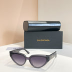 Balenciaga sunglasses with dark frames and purple-tinted lenses, gold logo on temple
