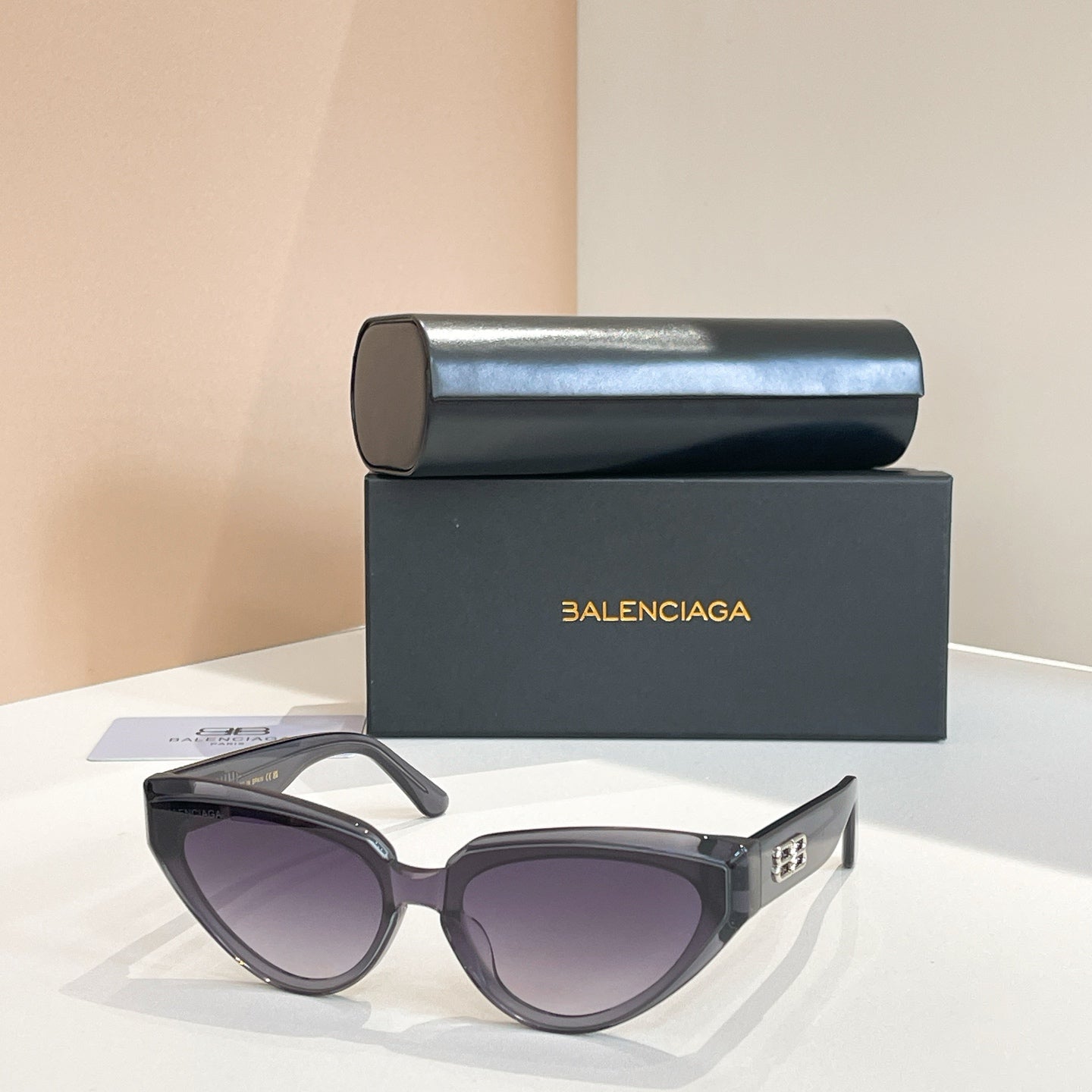 Balenciaga sunglasses with dark frames and purple-tinted lenses, gold logo on temple