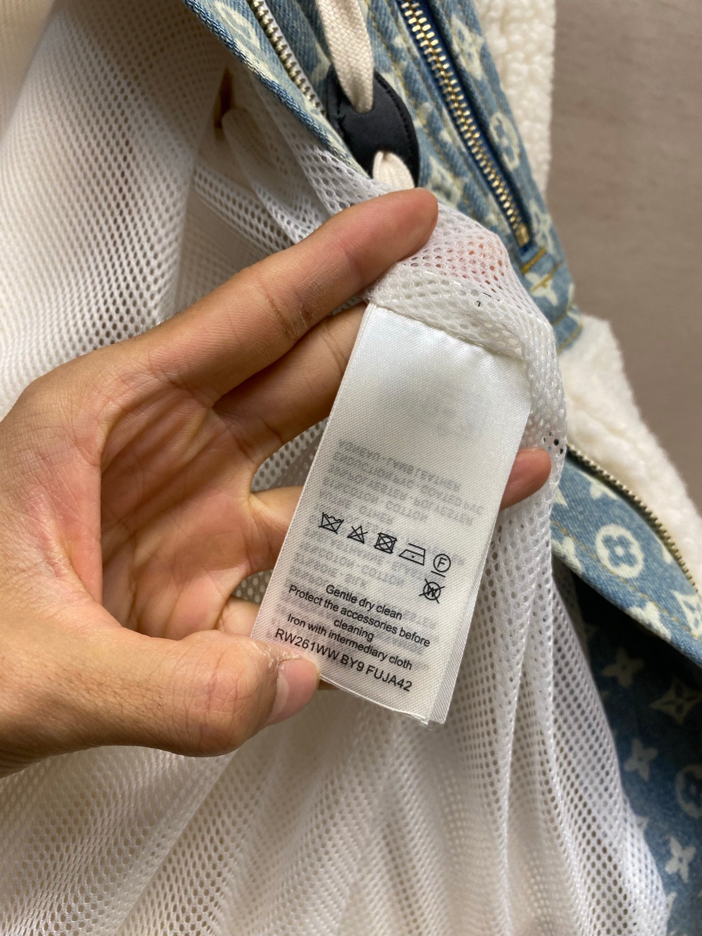 Interior care label on white sherpa lining near blue monogram zip