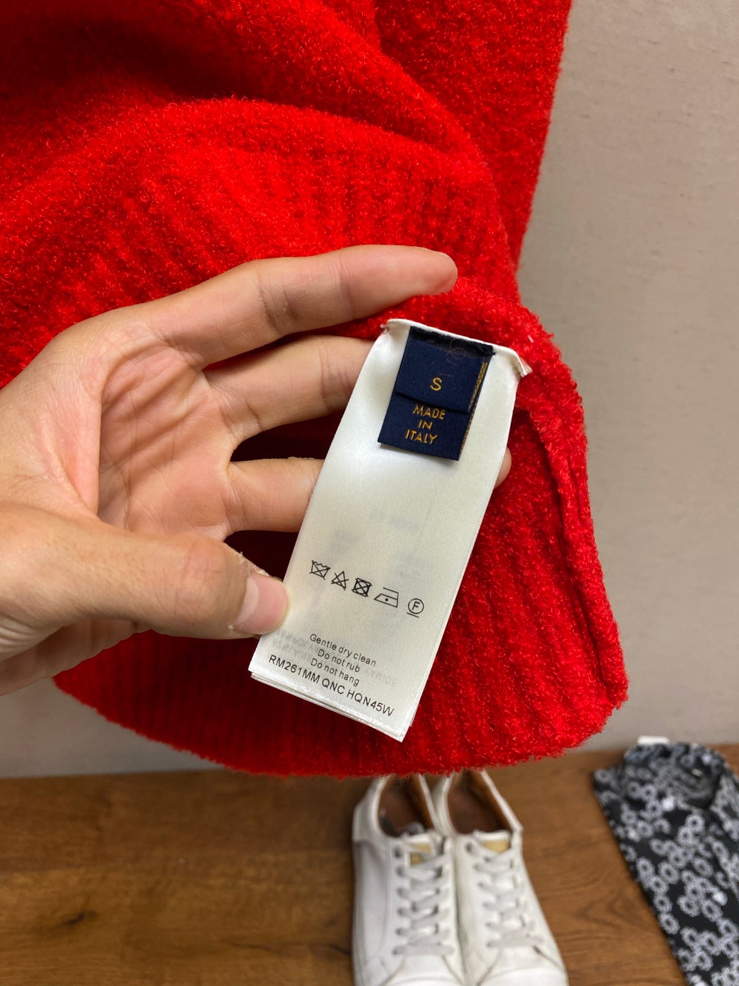Red sweater care and size label tag held in hand