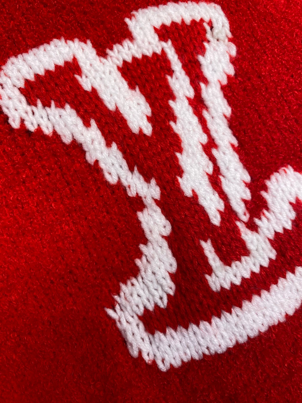 White Louis Vuitton monogram knit detail on red sweater