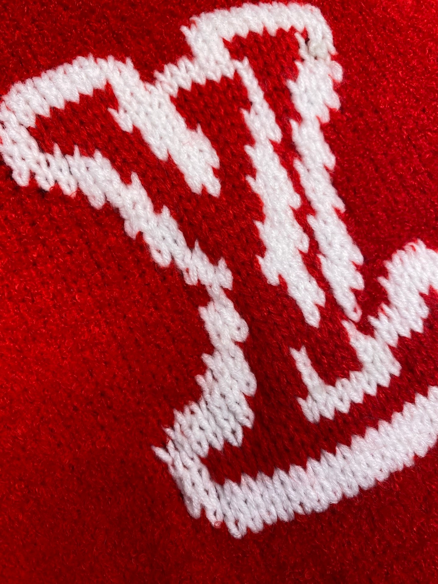 White Louis Vuitton monogram knit detail on red sweater