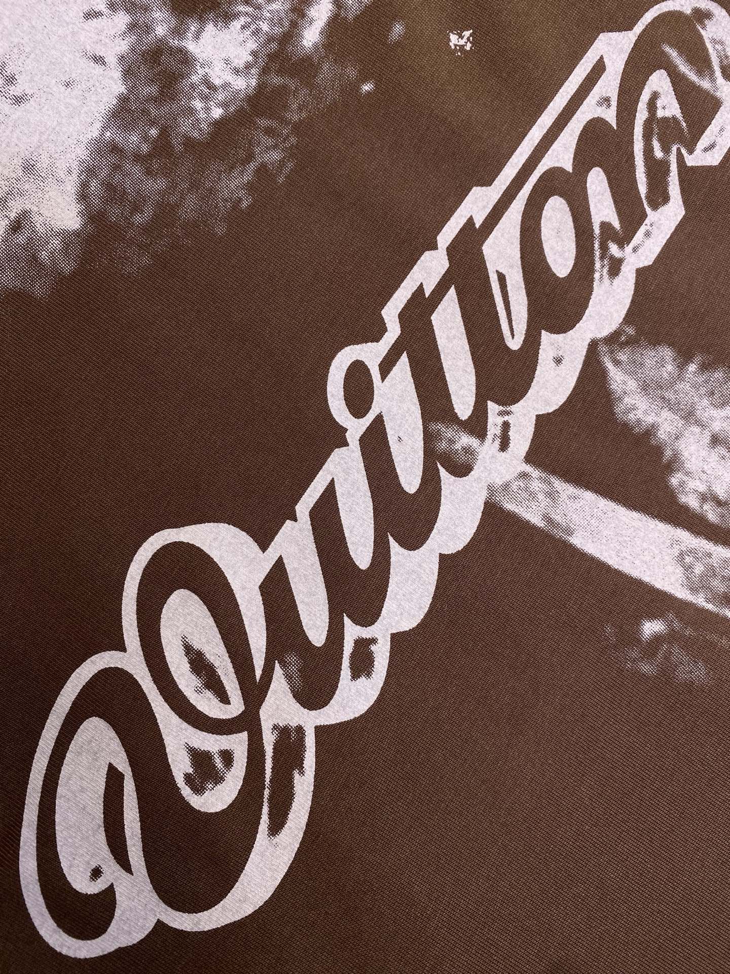 Louis Vuitton short-sleeve T-shirt fabric close-up with large white script print on dark brown