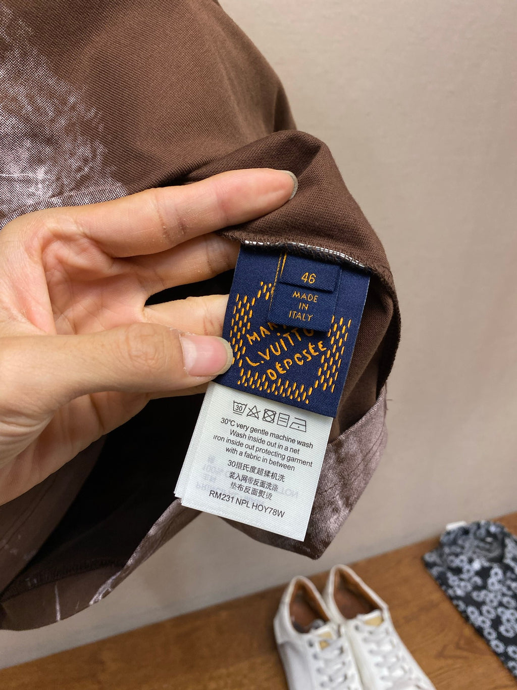Louis Vuitton T-shirt size label inside neck area with blue tag on dark brown fabric