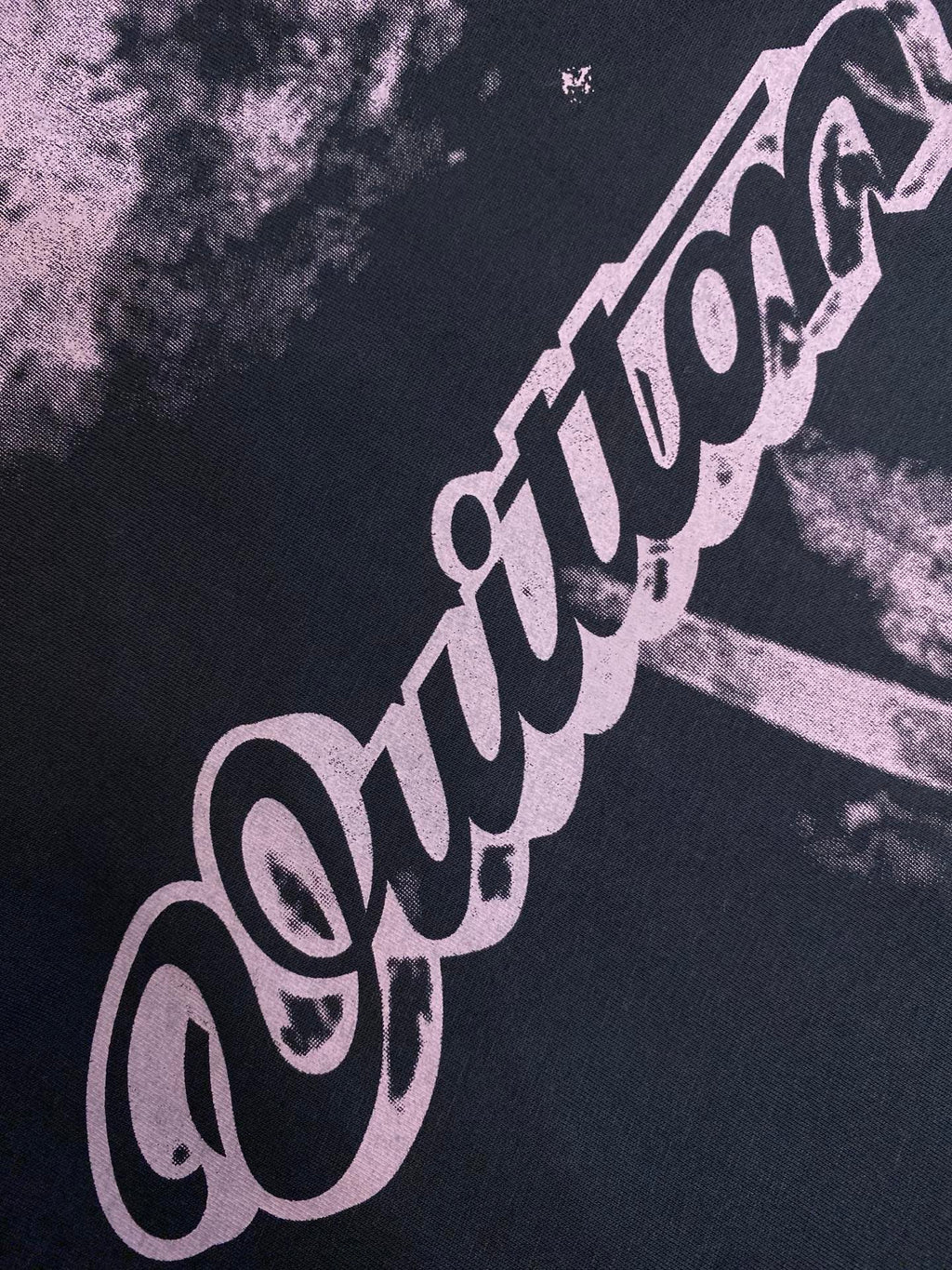 Purple logo lettering graphic on dark T-shirt fabric