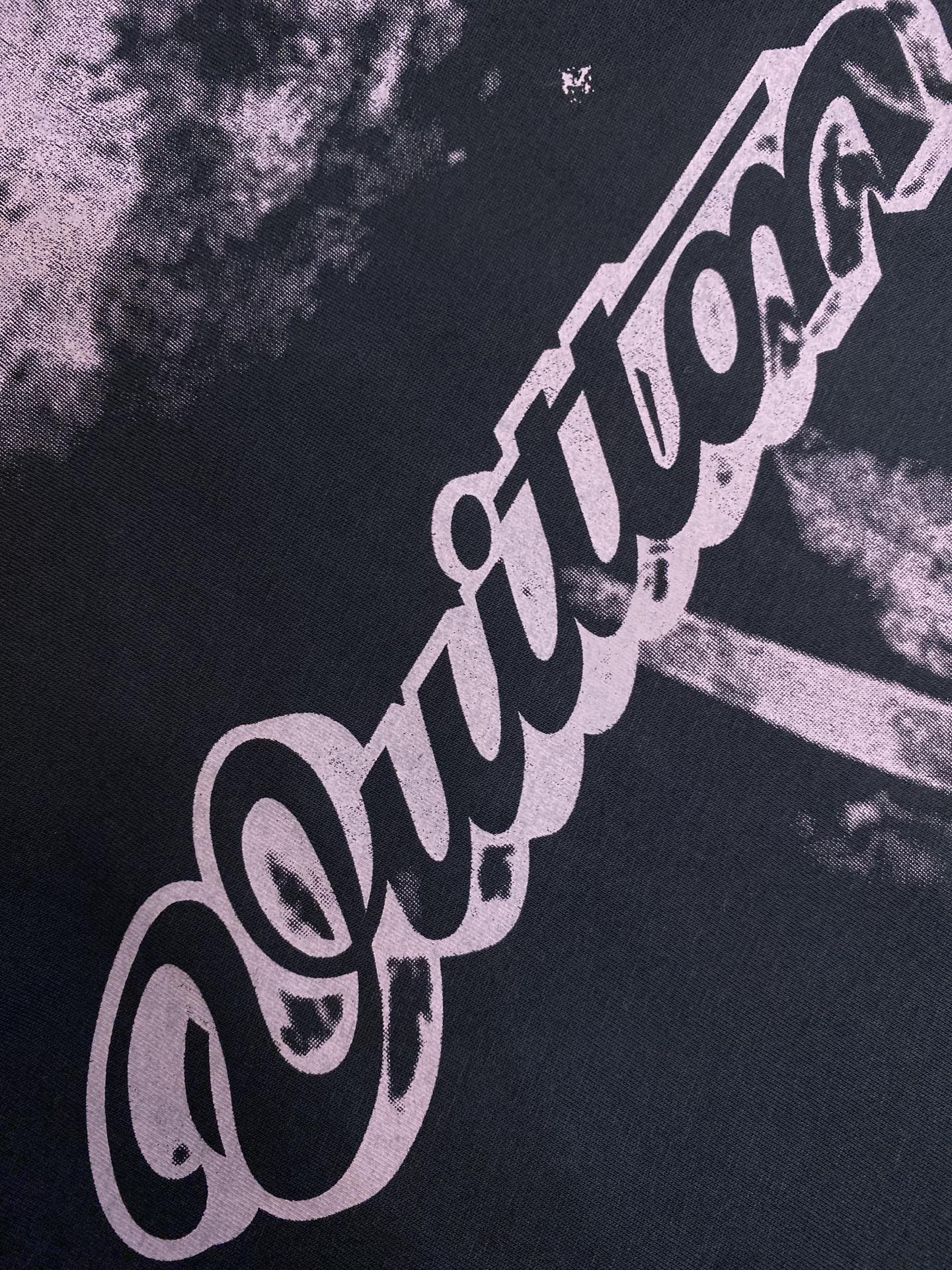 Purple logo lettering graphic on dark T-shirt fabric