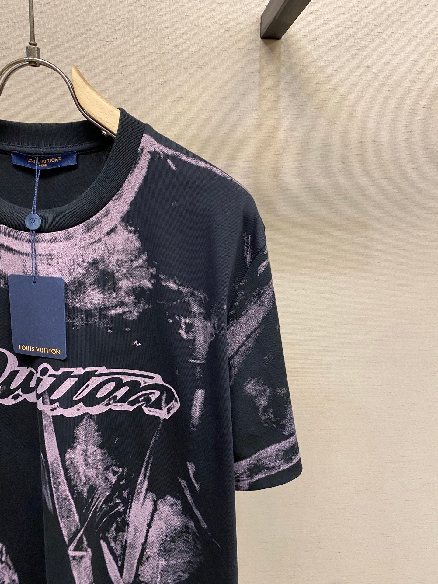 Graphic T-shirt with large purple logo text on dark base, short sleeves