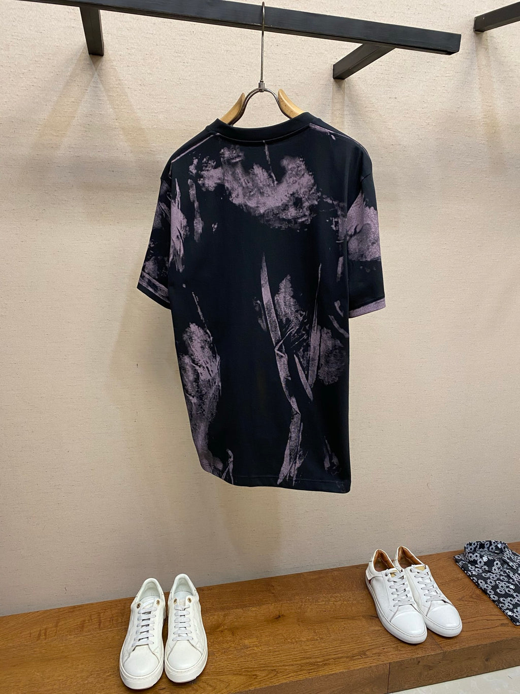 Graphic T-shirt with dark base and purple splatter print, back view, crew neck, short sleeves