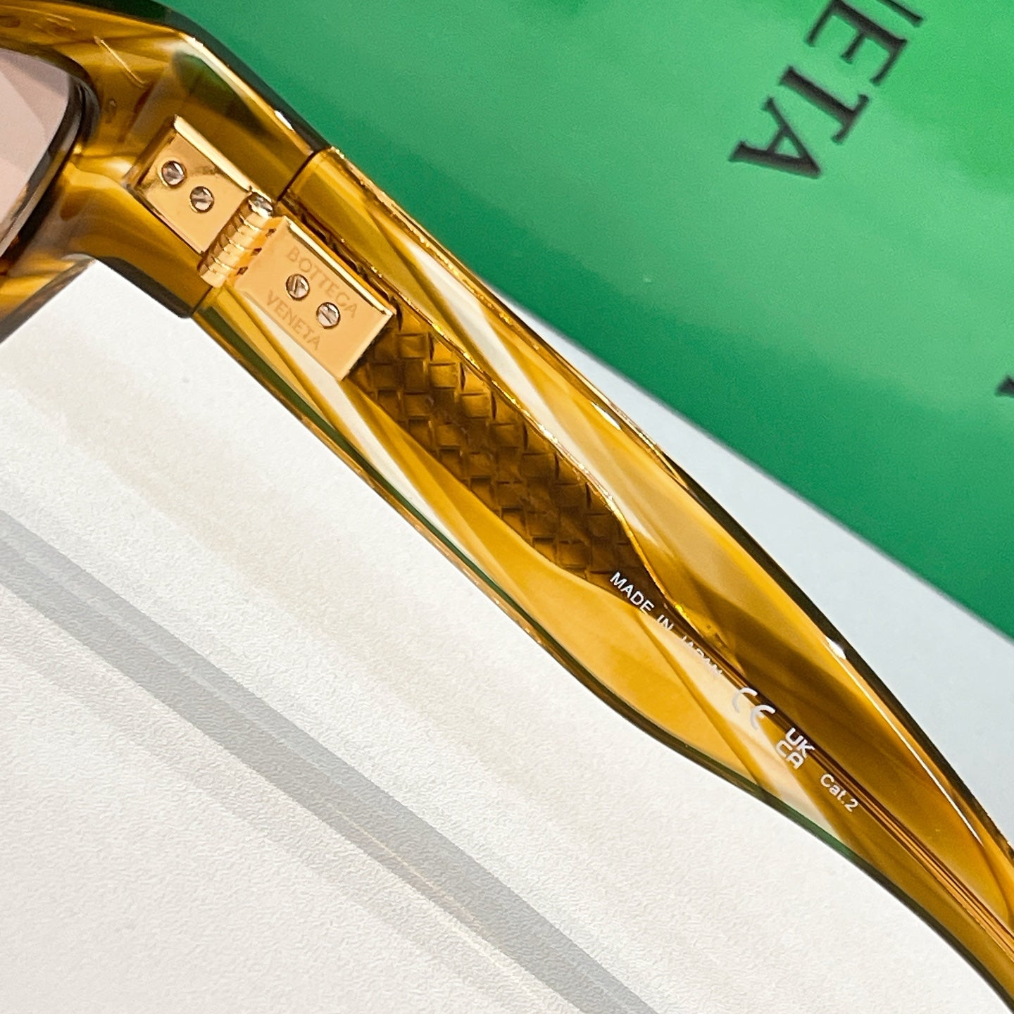 Close-up of amber sunglasses temple with textured detail and “Made in UK” marking