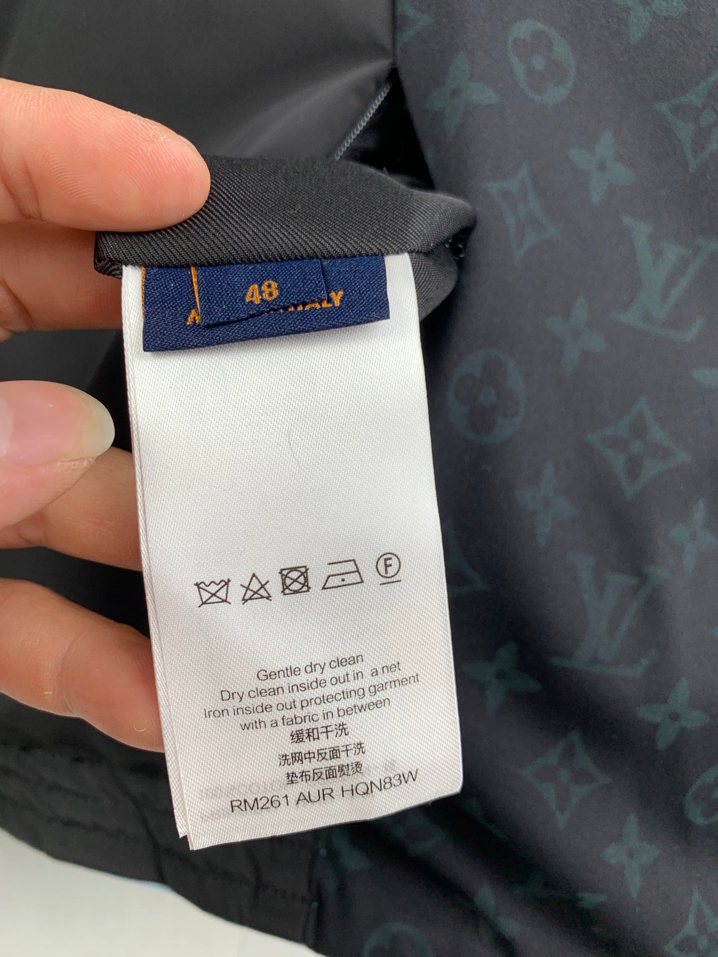 White size and care label on dark hooded jacket lining, blue size tag 48.