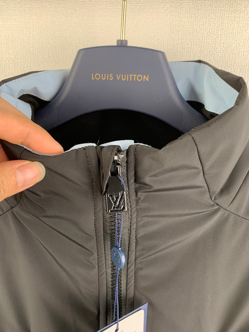 Dark gray hooded jacket neckline with zip pull and Louis Vuitton label in view.